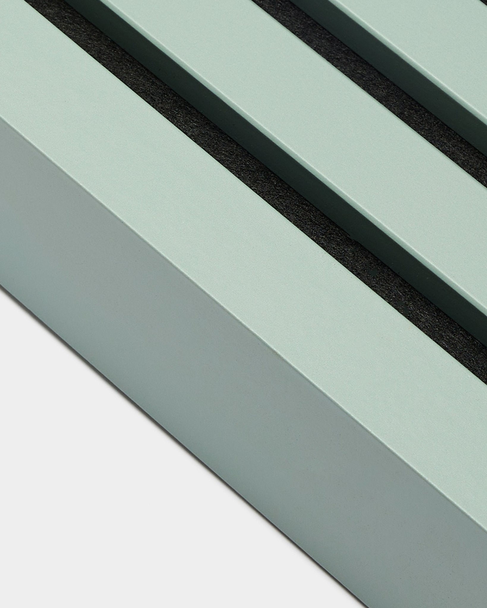 Vista aproximada do acessório de instalação WoodUpp Akupanel: lamela terminal em Cloud, 6,7 cm de largura, moldura em MDF verde-menta com dois sulcos black sobre fundo branco.